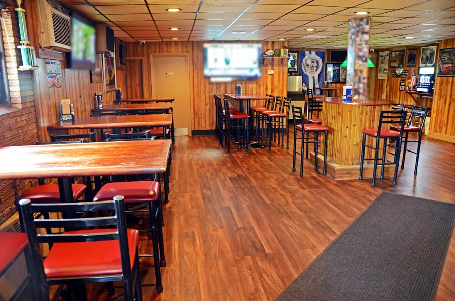 Dining room at Grand Crossing Bar & Grill with wood paneling, high-top tables and red stools
