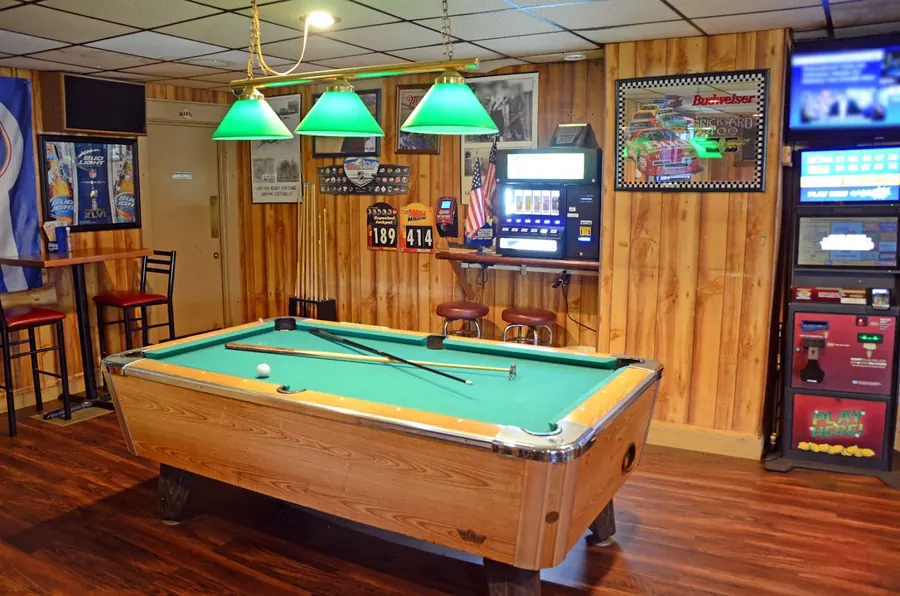 Pool table under green lamps in the game area at Grand Crossing Bar & Grill