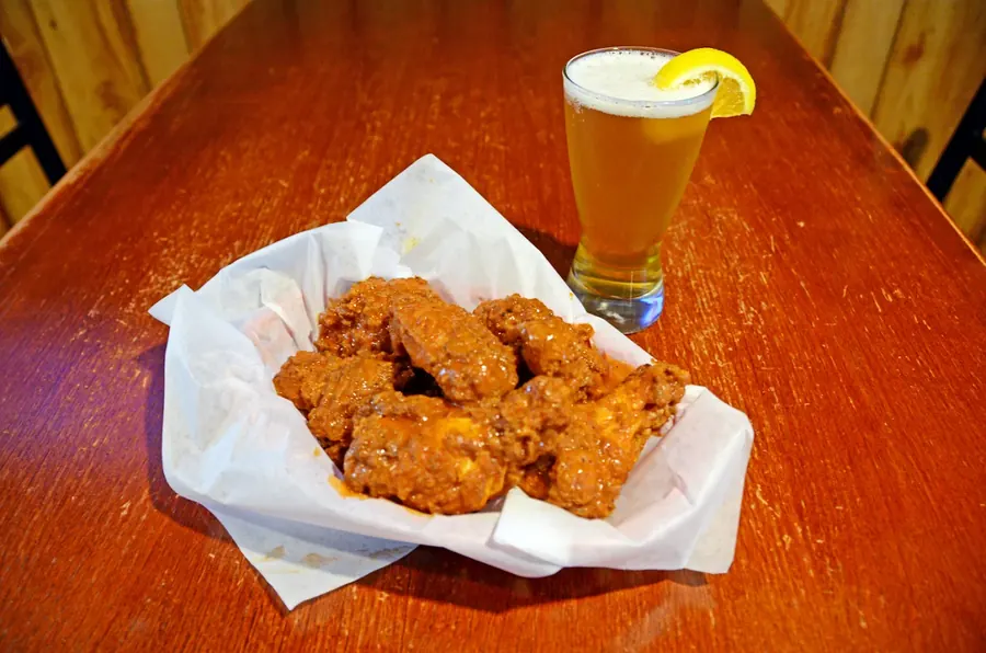 Sauced wings on deli paper served with a cold draft beer at Grand Crossing